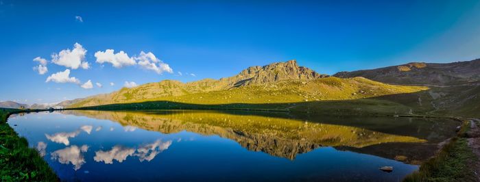 Scenic view of lake and mountains against blue sky