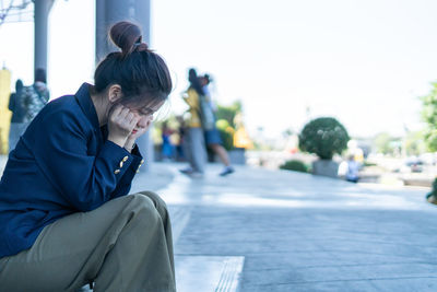 Man sitting on street in city