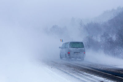 Cars on foggy weather against sky during winter