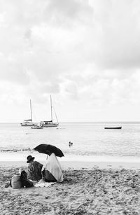Scenic view of people holding an umbrella at the beach against sky