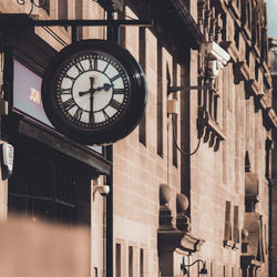 Low angle view of clock hanging on building