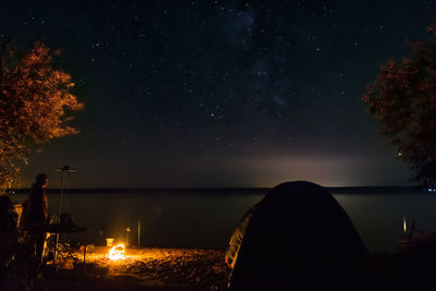 Silhouette on the shore of the lake near the fire. fisherman on the shore of the lake near the fire