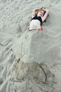 High angle view of girl buried in sand at beach