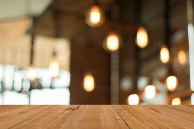Close-up of wooden table against illuminated lights