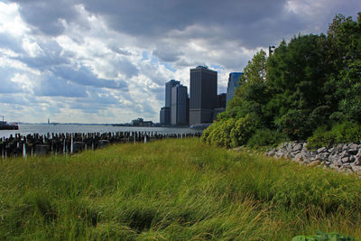 Scenic view of field by buildings against sky