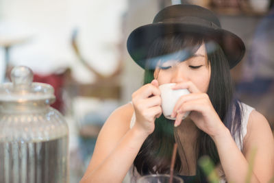 Close-up portrait of a young woman drinking glass