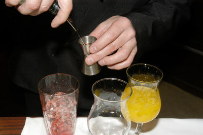 Midsection of people pouring wine in glass