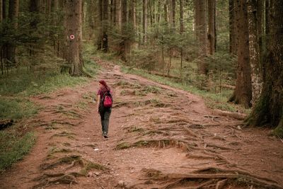Woman walking on dirt road in forest