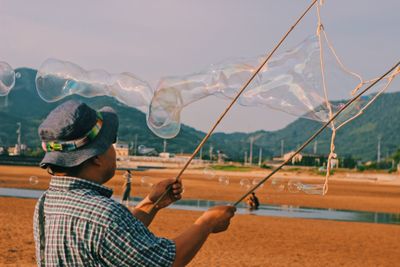 Portrait of man holding hat against mountain