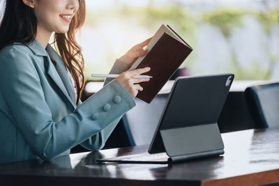 Midsection of businesswoman using laptop on table