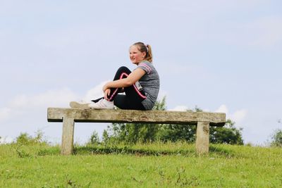 Portrait of girl sitting on wood against sky