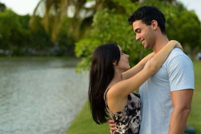 Side view of couple kissing against water