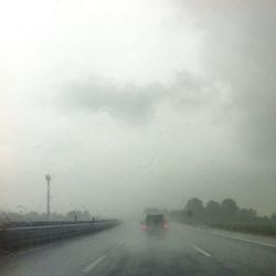 Cars on road against cloudy sky