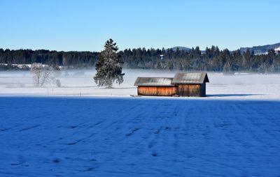 Built structure on frozen lake against clear blue sky