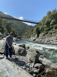 Man standing on rocks by water against sky