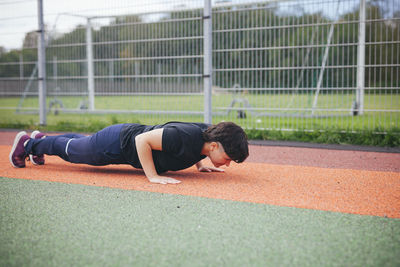 Young woman doing push-ups at outdoor gym