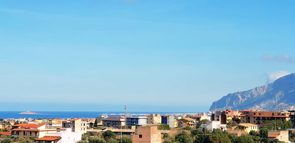 Townscape by sea against clear blue sky