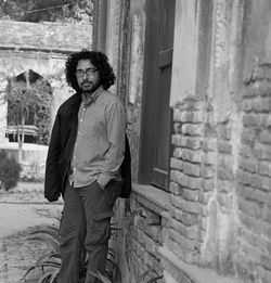 Full length portrait of young man standing against wall