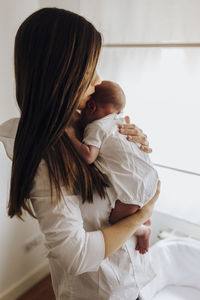 Side view of young woman with daughter at home