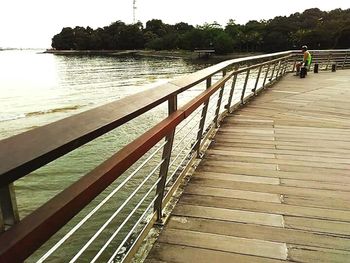 Jetty on footbridge over river against sky