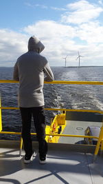 Rear view of man standing on boat against sea