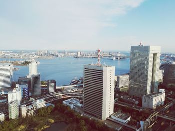 Cityscape by sea against sky