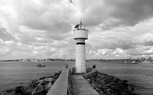 Lighthouse by sea against sky