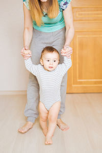 Midsection of mother and son standing on floor