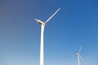 Low angle view of wind turbine against clear blue sky