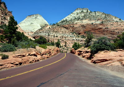 Road amidst rocky mountains against clear sky