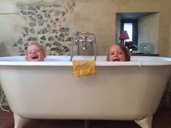 Happy siblings in bathtub at home