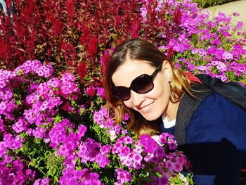 Close-up of smiling woman wearing sunglasses by flowers