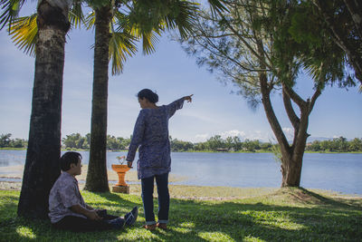 Woman pointing at lake to man in park