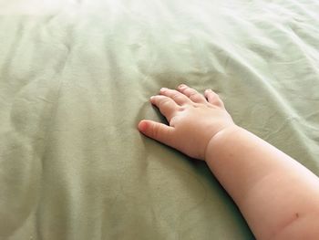 Cropped hand of baby on bed