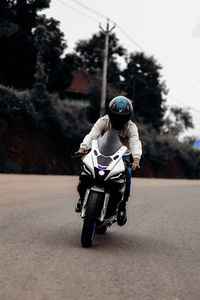 Side view of man riding motor scooter on road