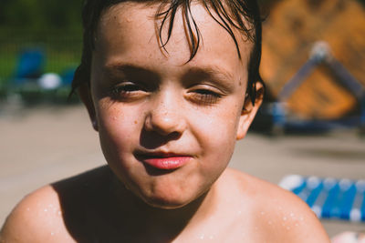 Close-up portrait of wet shirtless boy at poolside