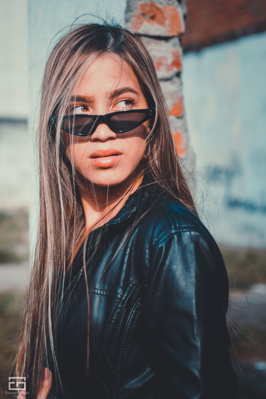 one person, real people, portrait, young women, lifestyles, young adult, glasses, focus on foreground, leisure activity, sunglasses, hair, smiling, fashion, casual clothing, hairstyle, jacket, front view, day, leather, outdoors, beautiful woman, leather jacket