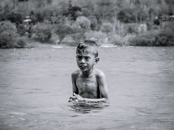 Shirtless boy looking away in lake