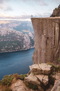 Man standing looking down at edge of cliff at preikestolen, norway