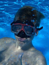 Portrait of cute boy wearing swimming goggles while swimming in sea