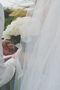 Cropped hands of groom giving bouquet to bride