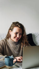 Portrait of young woman using laptop at home