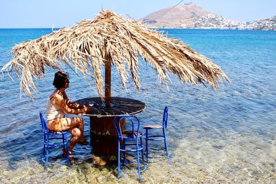 Woman on chair at beach against clear sky