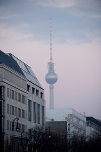 Communications tower in city against sky