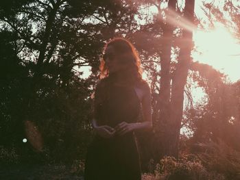 Rear view of woman standing by tree in forest