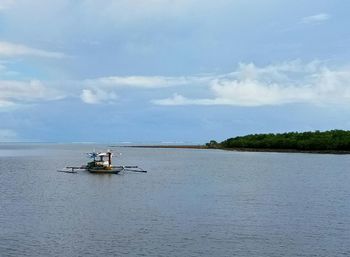 People on boat sailing in river against sky