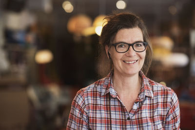 Portrait of smiling mature owner listening music using headphones