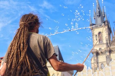 Young woman standing against blue sky