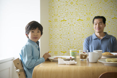 Portrait of boy having food with father at table