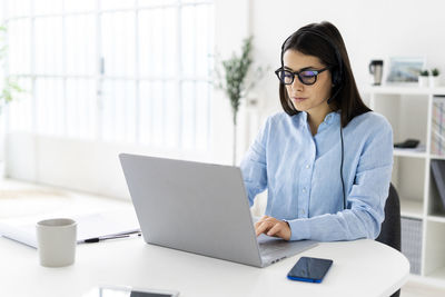 Woman using mobile phone while sitting on table